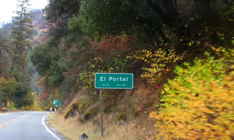 the El Portal community sign beside curving SR-140 under autumn foliage