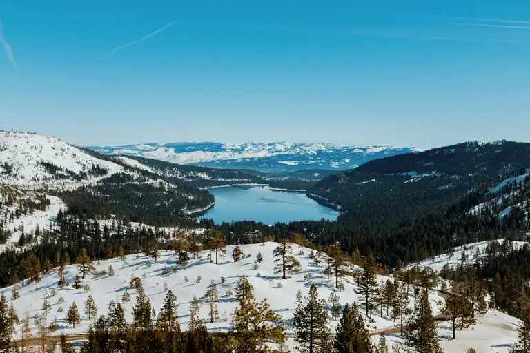 a snow-covered mountain forest and lake in the Tahoe region